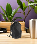 Two Pack Waterproof Rain Gear Storage Bags With Drawstring Pouches For Quick Access Rain Poncho Organizer For Cycling Hiking Camping And Travel next to a metal cup on a wooden table with plants in the background.