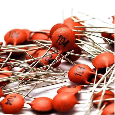 Close-up of ceramic capacitors from the Ceramic Capacitor Assortment Kit DIP 2pF To 100nF 30 Values 10 Pieces Each 300 Pieces Total 50V Rating Individually Bagged DIY Friendly For Prototyping And Hobby Electronics, showing orange components and metal leads.