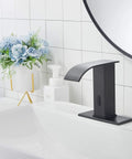 Automatic Sensor Matte Black Touchless Bathroom Sink Faucet With Drain Assembly beside a white sink and floral decor.