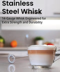 Stainless steel frother whisk next to a cappuccino cup on a kitchen counter, used for barista-style foam and mixing.