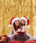 9.8 By 9.8 Feet 300 LED Curtain Lights With USB Plug illuminating a festive scene with two people wearing Santa hats indoors.