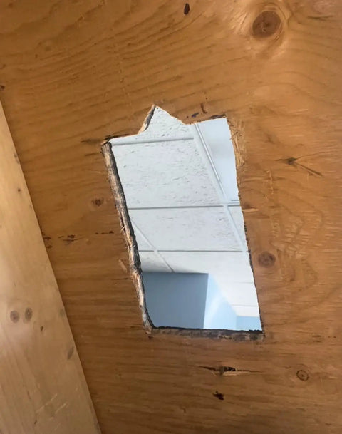 Cut-out section in plywood ceiling viewed from below, showing through to ceiling tiles, preparing for 3 Inch PVC Cast Iron And Copper Roof Pipe Flange For Inside Installation Over Shingles No Climb Required Works On Architectural Roofs Fits 3 Inch Pipes From Flat To 12 12 Pitch Weatherproof In Any Weather Including Snow Patented And Proven installation.