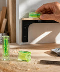 Bubble Level Vial, Spirit Level in green used for horizontal leveling on a wooden shelf with tools nearby.