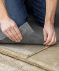 Hands laying carpet with Indoor Outdoor Carpet Tape One Point Four One Inch By Forty Two Feet White Fiberglass Reinforced Durable Adhesive.
