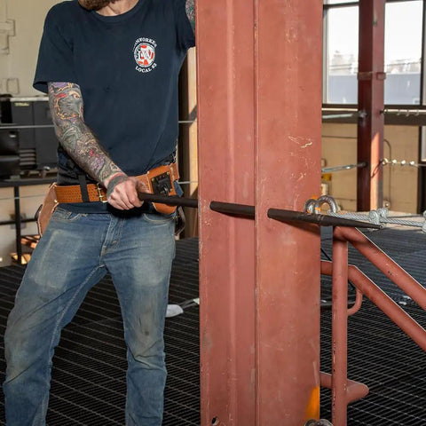 Worker using Made in USA Round 7/8 Inch by 36 Inch Connecting Bar for alignment on steel construction site.