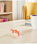 Orange bracket from 5 Piece Glider Plane Bracket Kit With Rubber Band Power For Do It Yourself Aircraft Builds on desk