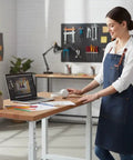 Rock Solid Height Adjustable Workbench With Premium Hardwood Surface And Hella Heavy Duty Steel Base Tough Garage Workstation For Daily Shop Jobs And Comfortable Ergonomic Workflow 48 X 24 Inch Table in a modern workspace with a woman using it.