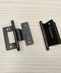 Pair of black metal cabinet hinges with mounting plates, top-down view for residential cupboards