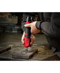 User operating Pro Grade M12 Fuel One Quarter Inch Cordless Straight Die Grinder Bare Tool for metalwork on steel plates.