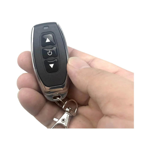 Hand holding remote of Dope Remote Control Switch Module For DC 3V To 12V Motors With Forward And Reverse Stop Mini RF Wireless Controller.