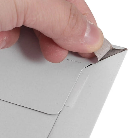 A hand peeling the seal of an A4 Gray White Self Sealing Paper Mailing Envelopes Thickened For Documents And Photos 30 Pack Great For Small Biz Shipping Easy Seal Mailers For Cards Invitations Postcards And Packages