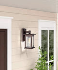 Dusk To Dawn Outdoor Wall Light With Seedy Glass In Vintage Farmhouse Bronze Finish 12.25 Inch Sconce mounted by a door