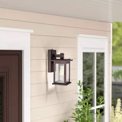 Dusk To Dawn Outdoor Wall Light With Seedy Glass In Vintage Farmhouse Bronze Finish 12.25 Inch Sconce mounted by a door