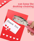 Heart And Star One Quarter Inch Metal Handheld Paper Punch Set With Soft Handled Design punching hearts into red paper for crafting.