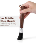 Hand holding Two Pack Coffee Grinder Cleaning Brush With Natural Walnut Wood Handle And Black Boar Bristle For Grinders Espresso Machines Barista Tools Hanging Loop