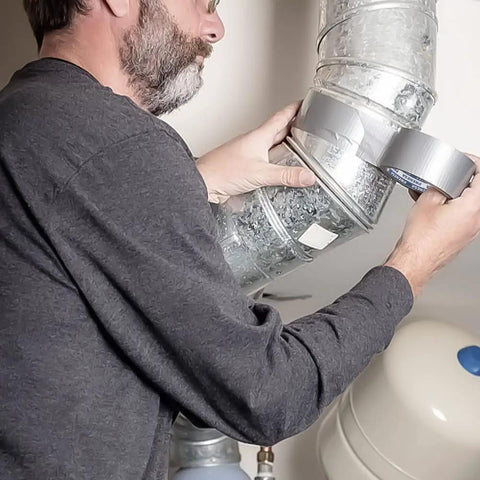 Man applying Beefy Heavy Duty Waterproof Duct Tape 1.88 Inch Wide By 35 Yards Strong Adhesive for sealing metal ductwork