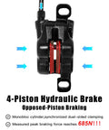 Front view of black 4-piston hydraulic MTB disc brake caliper with red pistons.