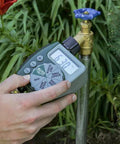Hand holding Programmable Digital Hose Watering Timer With LCD Screen Battery Powered One Outlet Irrigation Timer near faucet