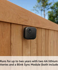 Full Wireless Outdoor Security Camera Kit And Smart Hardwired Doorbell Package Serving Straight Fire 2K Video All Weather Durable Black Finish Plus Sync Hub on wooden fence.