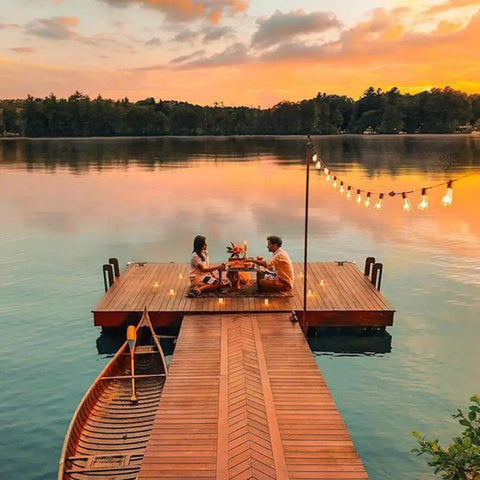 Couple dining on dock at sunset with Outdoor String Lights 30ft With 25 Plus 2 Spare LED Filament Bulbs, Dimmable, Shatterproof And Waterproof.