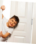 Child smiling while peeking through a partially opened door showcasing heavy duty hinges.