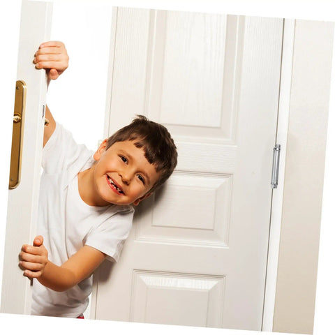 Child smiling while peeking through a partially opened door showcasing heavy duty hinges.