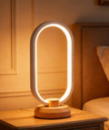Modern Ellipse LED Desk Lamp with Wood Accent on nightstand, dimmable warm white night light, cozy vibes lighting.