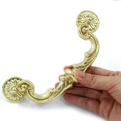 4 Pack 150 Mm Center To Center Pull Handles With Drop Down Bail Swing Zinc Alloy Rustic Vintage Style Antique Drawer Pulls For Kitchen Cabinets Gold Finish Durable Zinc Alloy Construction Includes Two Screw Types For Easy Installation, hand holding one handle