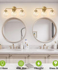 Three Light Vanity Wall Sconce Over Mirror In Matte Gold Finish With Transparent Glass Ball Shade in bathroom setting