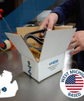 Hands holding a cardboard box labeled MDS with conveyor belt inside, West Michigan based logo visible on box, on a table.