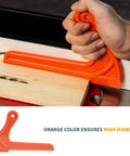 Hand using an orange push stick from the Table Saw Safety Accessories 6-Piece Set With Push Block, Push Sticks And Taper Jig For Router Tables.