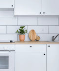 Hella Durable Self Adhesive Cabinet Knobs Top Shelf Hardware Super Sleek Black Finish For Kitchen Drawers And Cupboards, kitchen with black knobs and potted plant.