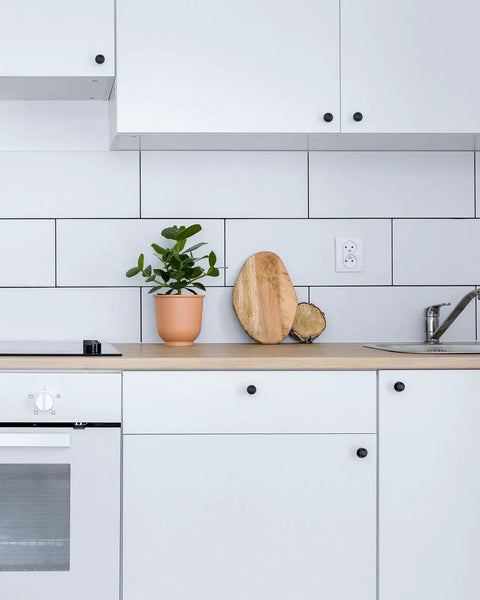 Hella Durable Self Adhesive Cabinet Knobs Top Shelf Hardware Super Sleek Black Finish For Kitchen Drawers And Cupboards, kitchen with black knobs and potted plant.