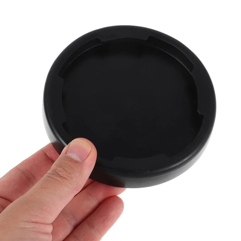 Hand holding black shock absorbing floor pad for home gym 4 pack non slip base mats for treadmills elliptical machines.