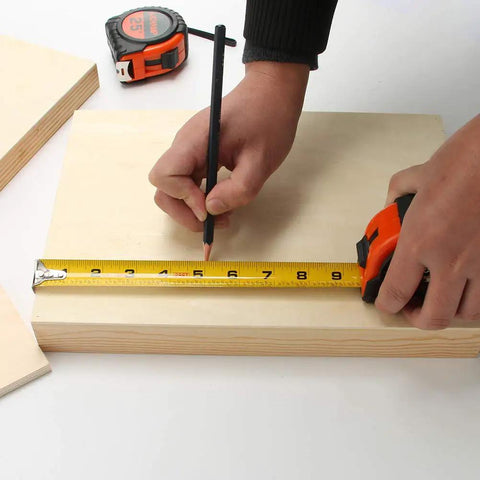Person marking wood with 25 ft retractable measuring tape, Bulk Six Pack 25 Ft Tape Measure With Easy Read Fractions One Eighth Increments.
