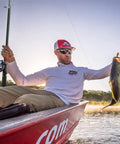 Man holding fish with telescopic fishing rod and reel combo set with carbon fiber rod and stainless steel baitcasting reel on a boat