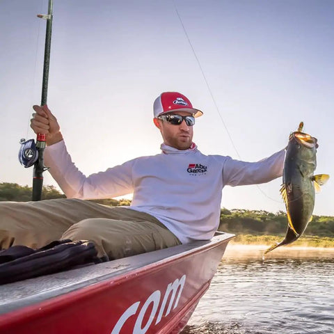 Man holding fish with telescopic fishing rod and reel combo set with carbon fiber rod and stainless steel baitcasting reel on a boat