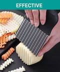 Side view of large stainless steel crinkle cutter with black handle slicing potatoes into crinkle-cut fries.