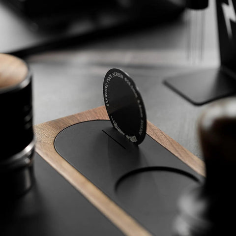 Close-up of All In One Dope Espresso Tamping Station with distributor and tamper holder on wooden surface.