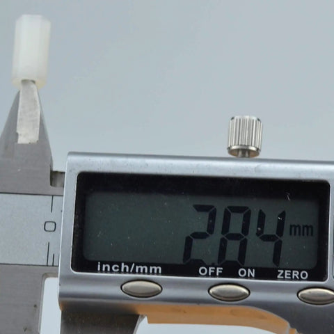 Measuring Real Deal White Nylon Hex Standoff 100 Pack M3x12mm with caliper, showing 28.4mm length on display.
