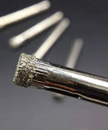 Close-up of diamond-coated hole saw bit tip; silver metal with gritty coating for drilling drainage holes in plant pots