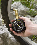 Close-up of JACO Elite low-pressure tire gauge with brass nozzle attached to a bicycle tire valve