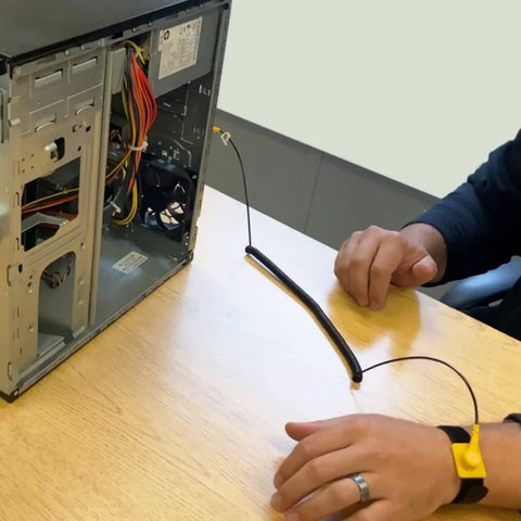 Person using Anti Static Wrist Strap Kit With 11 Inch Grounding Wristband, Alligator Clip, Extendable Long Cable, Adjustable 6 To 8.5 Inch Wrist, Protect Your PC From Static Shocks Like A Pro, connected to an open desktop computer on a table.