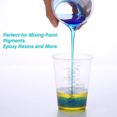 Hand pouring blue liquid into 100 Pack 8oz Graduated Clear Plastic Measuring Cups with Wooden Stirring Sticks for Mixing Paints Pigments Epoxy Resins
