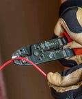 Electrician using American Made Multi Tool Wire Stripper Cutter And Crimper For 8-22 AWG on red wire in gloved hands.