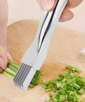 Mandoline slicer with stainless steel blades slicing green onions on a wooden cutting board