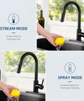 Friho Matte Black Kitchen Faucet with Pull Down Sprayer in stream mode, washing a lemon in a kitchen sink.