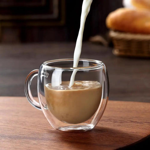 Cream being poured into a Double Wall Insulated Espresso Cups Set Of Two Borosilicate Glass Demitasse Mugs With Handle.