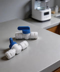 Two 3/8 Inch Quick Connect Shut Off Ball Valves, polypropylene material, blue handles, for water filter lines on a grey countertop.