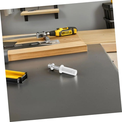 Close-up of white plastic pivot hinge pin with metal axle on a gray worktable; tools and wood in background.